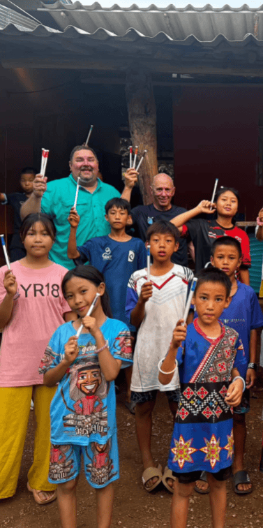 Children and adults hold toothbrushes during a dental health outreach visit in their community.