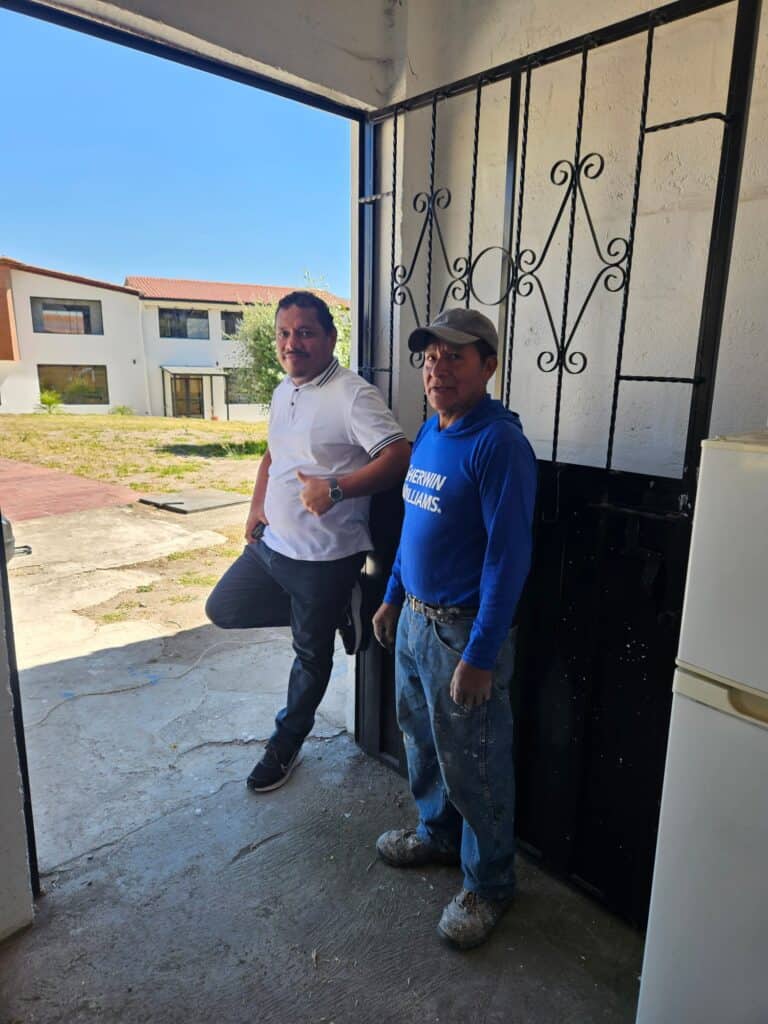 Two Ecuador project partners stand together at a building entrance.