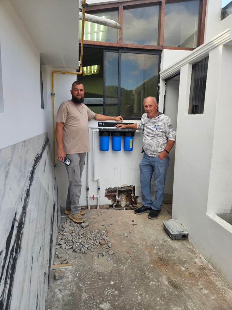 Project partners stand beside a water filtration system installed in an Ecuadorian community.